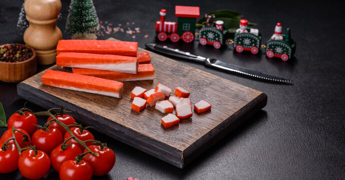 Crab sticks on a cutting Board with a knife. On a black christmas table