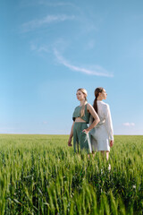 Two fashion woman in the green field. Freedom travel. Summer landscape.