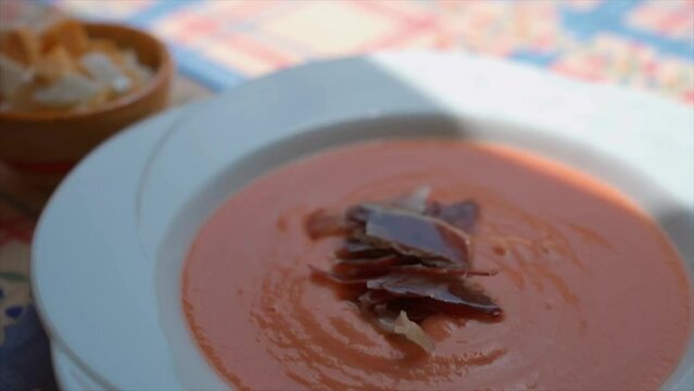 Garnishing Salmorejo with jam&oacute;n, Spanish tomato soup