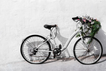 photo of a black and white vintage bicycle with flowers on a white wall