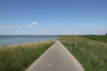 a dutch coast landscape in zeeland with a path on top of the seawall with a view at the blue...