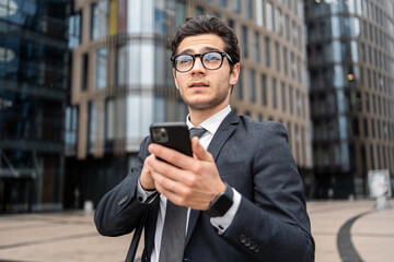 A businessman man uses a phone in his hands writes a message reply to a colleague by mail.