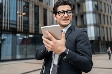 An entrepreneur with glasses, a man uses a tablet in his hands writes a reply message via the...