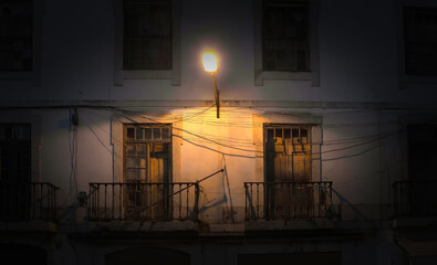 A lantern shines at night over two small balconies in an old building. Abstract background. Lisbon, Portugal.