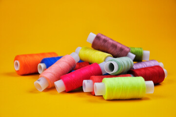 Coils with multicolored threads on a yellow background. Blurring background.
