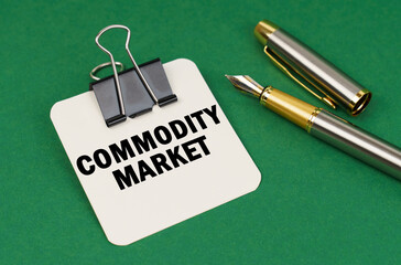 On a green surface, a pen and a sheet of paper with the inscription - Commodity market