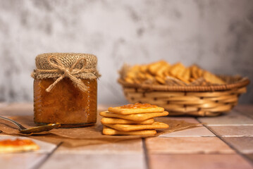 Homemade jam. A glass jar of sea buckthorn jam on a gray background. Homemade sea buckthorn marmalade and crackers on the kitchen table.