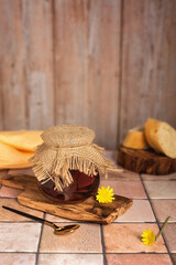 Fototapeta na wymiar Homemade jam. A glass jar of dandelion jam on a beige background. A jar of dandelion jam on a wooden board and pieces of baguette on a beige kitchen table.