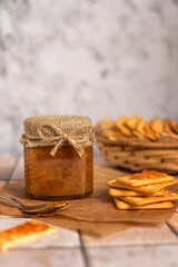 Homemade jam. A glass jar of sea buckthorn jam on a gray background. Homemade sea buckthorn marmalade and crackers on the kitchen table.