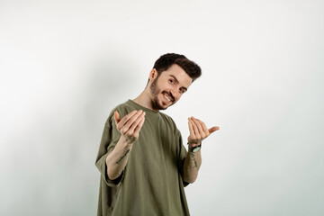 Caucasian young man wearing t-shirt posing isolated over white background inviting to come closer with hands. Happy that you came. - obrazy, fototapety, plakaty