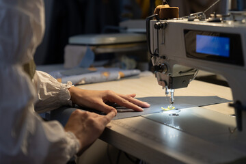 Woman tailor work on sewing machine stitching patterns of new collection. Closeup shot of female...