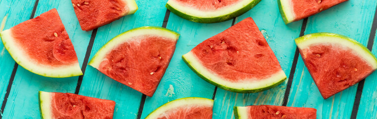 Narrow view of slices of fresh juicy watermelon against a blue background.