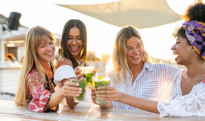 Multiracial girls having fun at chiringuito on the beach while drinking mojito -Young women laughing together during happy hour