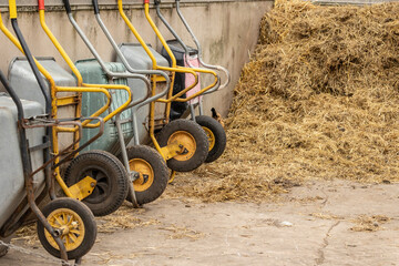 close up of upright stacked wheelbarrows with yellow wheels in a farm yard