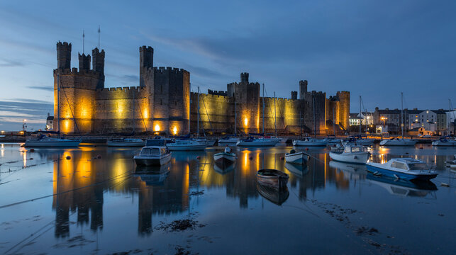 Caernarfon castle during the blue hour high tide lights reflected in sea long exposure