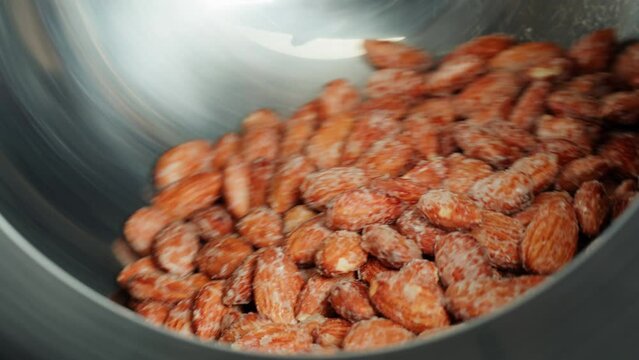 Fried almond in sugar, production of sugared nuts. Factory of healthy sweet food. Cooking dessert snack close-up. 
