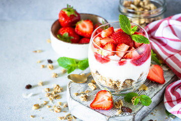 Parfait with cream or yogurt, jam and fresh strawberries in the glass jar.