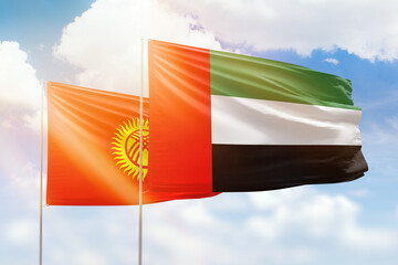 Sunny blue sky and flags of united arab emirates and kyrgyzstan