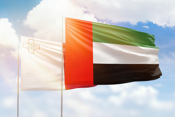 Sunny blue sky and flags of united arab emirates and malta