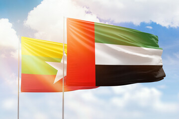 Sunny blue sky and flags of united arab emirates and myanmar