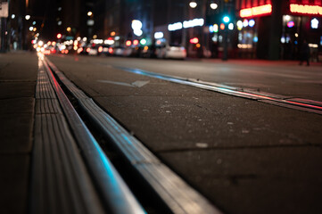 Street level selective focus on trolley rail lines at night in San Diego.