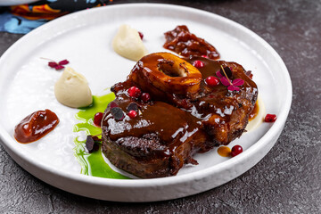 Stew veal shank meat OssoBuco, italian osso buco steak. Black wooden background. Top view. Copy space