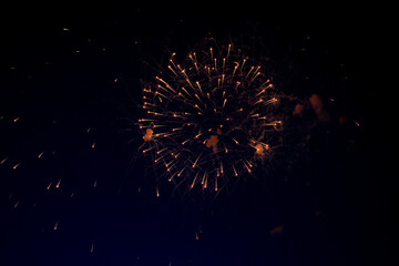 A bright ball of fireworks with orange sparks and a lot of sparks around on the background of the...