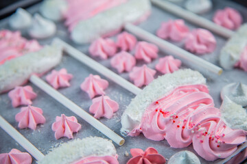 Meringues in the form of pink Christmas hats with a pompom and a white lapel on a stick lie on...