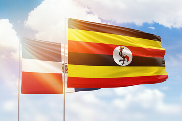 Sunny blue sky and flags of uganda and dominican republic
