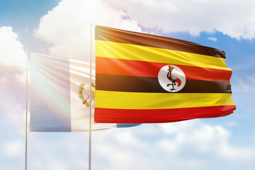 Sunny blue sky and flags of uganda and guatemala