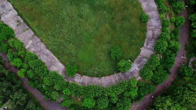 Drone aerial footage of the abandoned stadium in the trees and greens, 4k