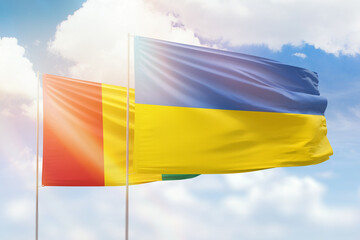 Sunny blue sky and flags of ukraine and guinea