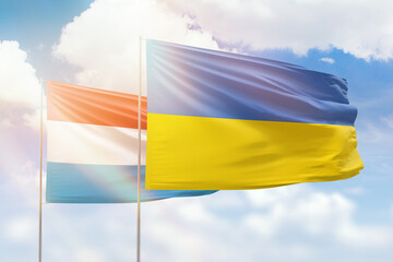 Sunny blue sky and flags of ukraine and luxembourg