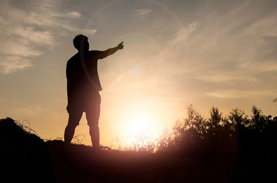 Silhouette man standing and Show hand see sun up.freedom,happy,feel good.Photo concept active and nature background.