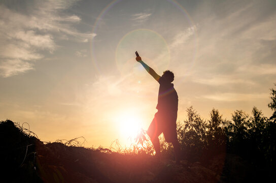 Silhouette man standing and Show hand see sun up.freedom,happy,feel good.Photo concept active and nature background.