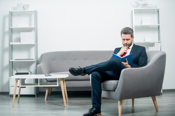 thinking mature businessman in suit sit in office reading book