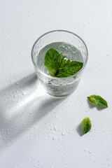 glass of water with mint, water drops on white background