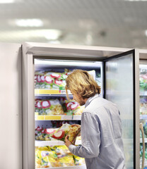 Man choosing frozen food from a supermarket freezer... choosing a dairy products at supermarket, reading product information