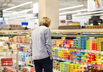 Man choosing frozen food from a supermarket freezer... choosing a dairy products at supermarket, reading product information