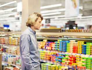 Man choosing frozen food from a supermarket freezer... choosing a dairy products at supermarket, reading product information