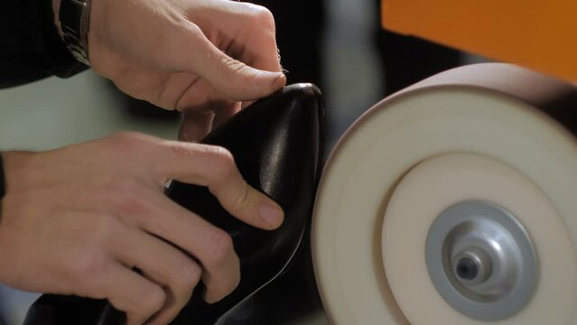 Shoemaker, shoes master using automatic shoe polish machine tool for polishing black leather women footwear at workshop - close up