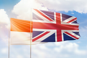 Sunny blue sky and flags of united kingdom and indonesia