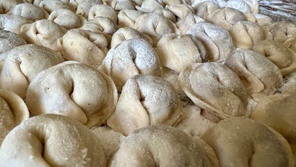 grandmother for 80 years with love prepares dumplings she is the guardian of the family, she wears a white scarf and a blue jacket, she sits in the kitchen and sculpts dumplings and dumplings shakes