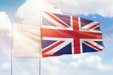 Sunny blue sky and flags of united kingdom and malta