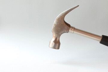 An iron hammer hangs over an empty space on a gray background. Free space for text.