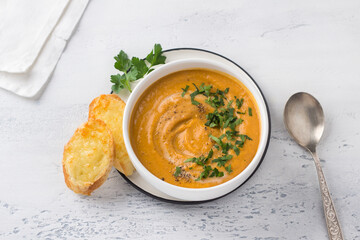 Lentil cream soup with parsley and cheese croutons on a light blue background