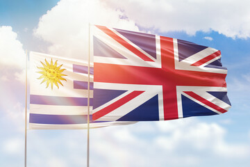 Sunny blue sky and flags of united kingdom and uruguay