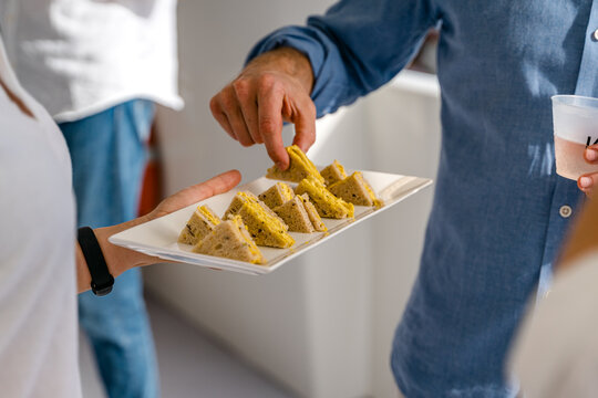 Un homme se sert une mignardise sur une assiette amen&eacute;e par une serveuse