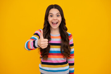 Amazed teenager. Excited teen girl. Happy casual teenager child girl showing thumb up and smiling isolated on yellow background.