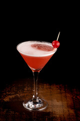 angle view martini glass with cherry and foam dark background on wooden table